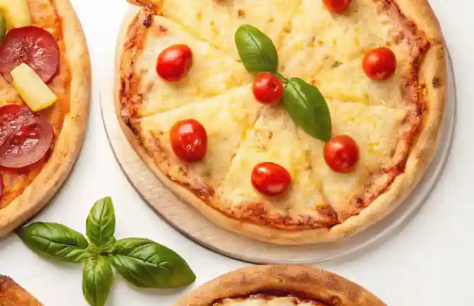 A freshly baked Margherita pizza topped with cherry tomatoes and basil leaves, served on a round pizza tray with additional pizzas in the background.